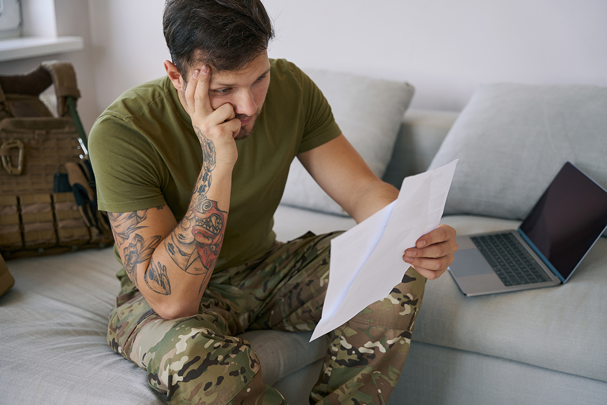 Stressed out military man reading document and rubbing his temple